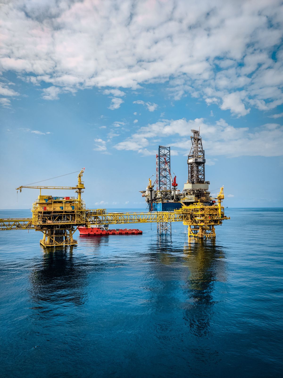 Offshore oil rig reflecting on calm ocean waters